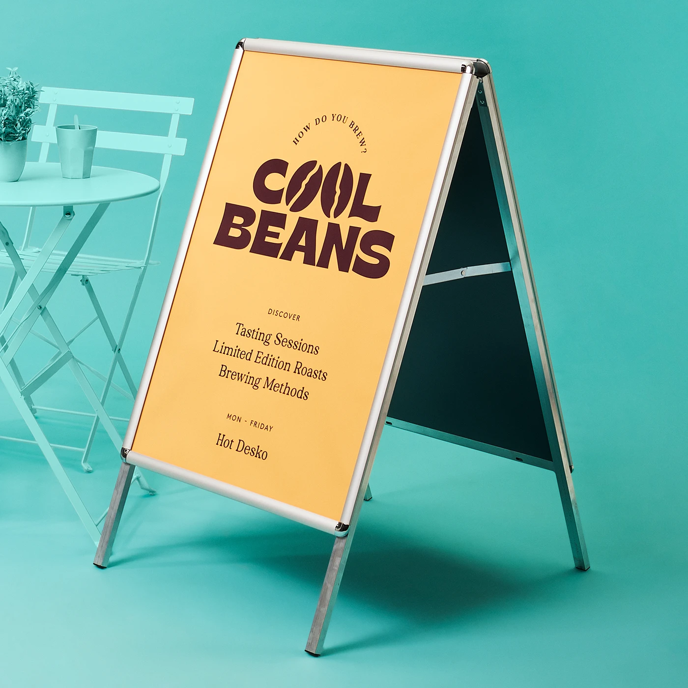 A double-sided A Board sign on a teal background features a yellow poster for "COOL BEANS" coffee, advertising tasting sessions, limited edition beans, and brewing methods.