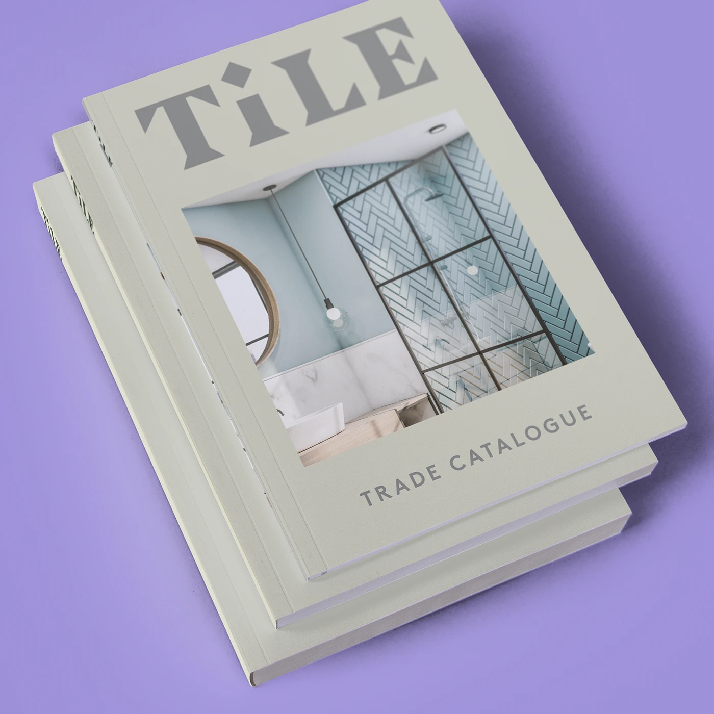 Three stacked perfect bound books with a modern trade catalogue design on a purple background.