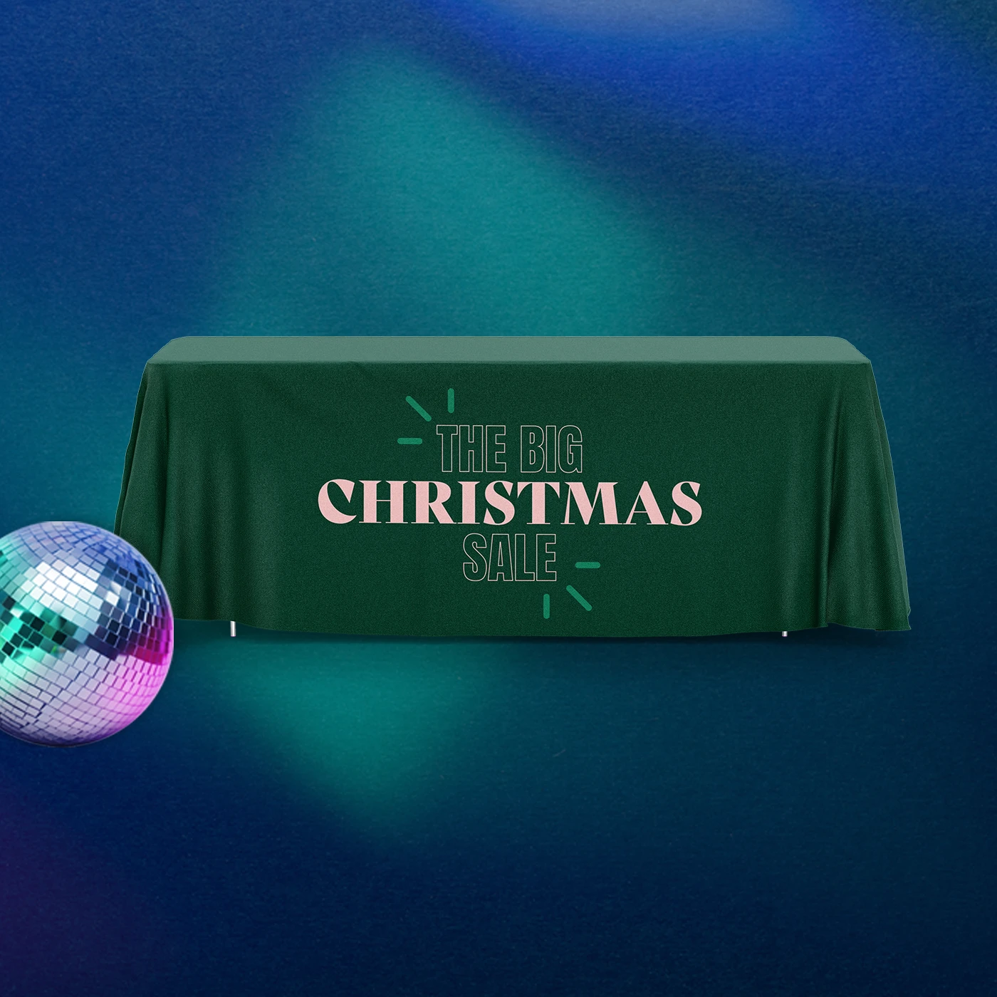 Green tablecloth placed over a rectangular table, feautring pink text reading 'The Big Christmas Sale', against a dark blue background beside a colourful disco ball.