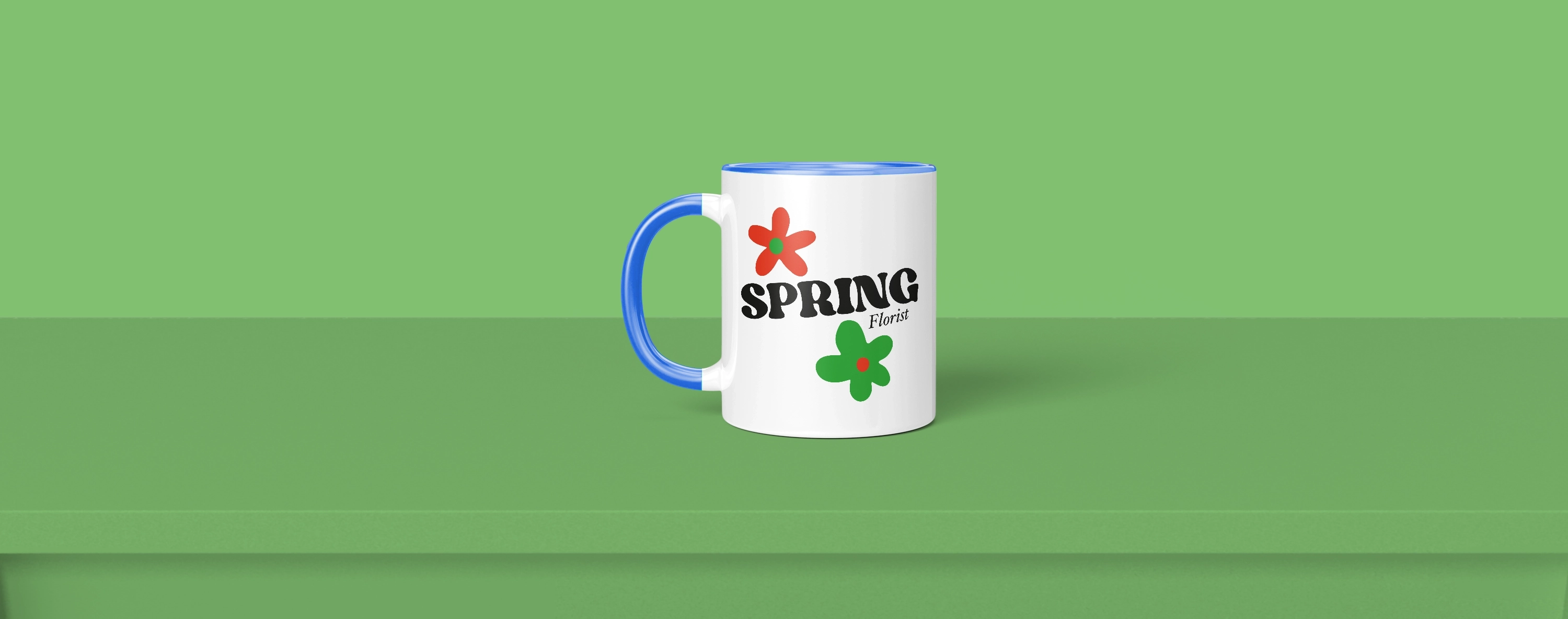 White ceramic mug with blue handle and rim, placed on green surface against green background.