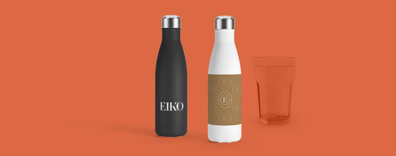 Two bottles and a tinted glass arranged on orange background, featuring printed branding and label details.