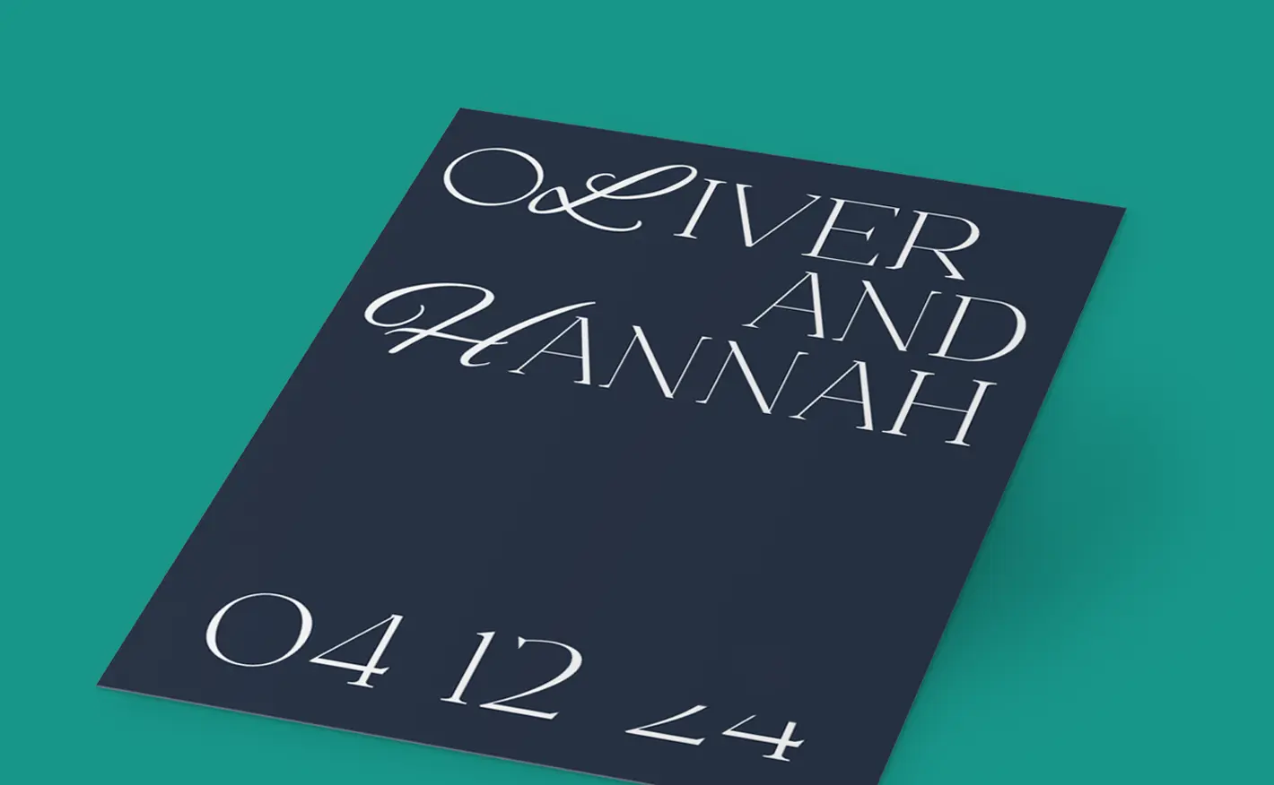 Dark navy Wedding Invitation card with elegant white ink typography placed on a teal surface; the card reads “OLIVER AND HANNAH” in decorative script, with the date “04 12 24” below.