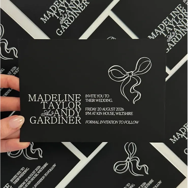 Elegant black wedding Save the Date card, featuring white ink text and ribbon graphics.