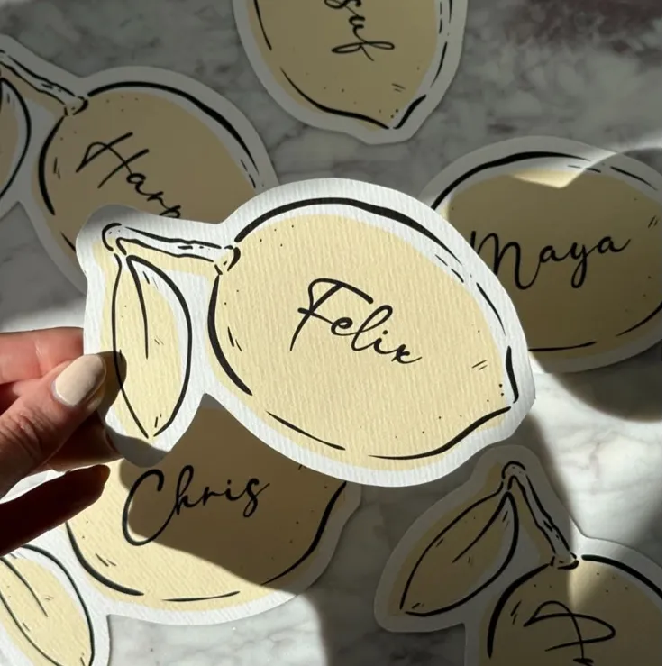 Yellow lemon-shaped Wedding Place Cards with cursive guest names.