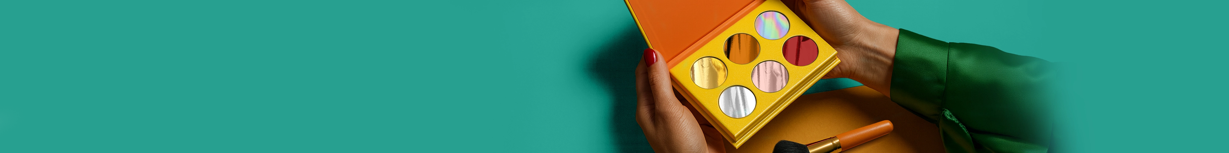 Lady holding a makeup palette with six metallic colours inside, on a blue background.