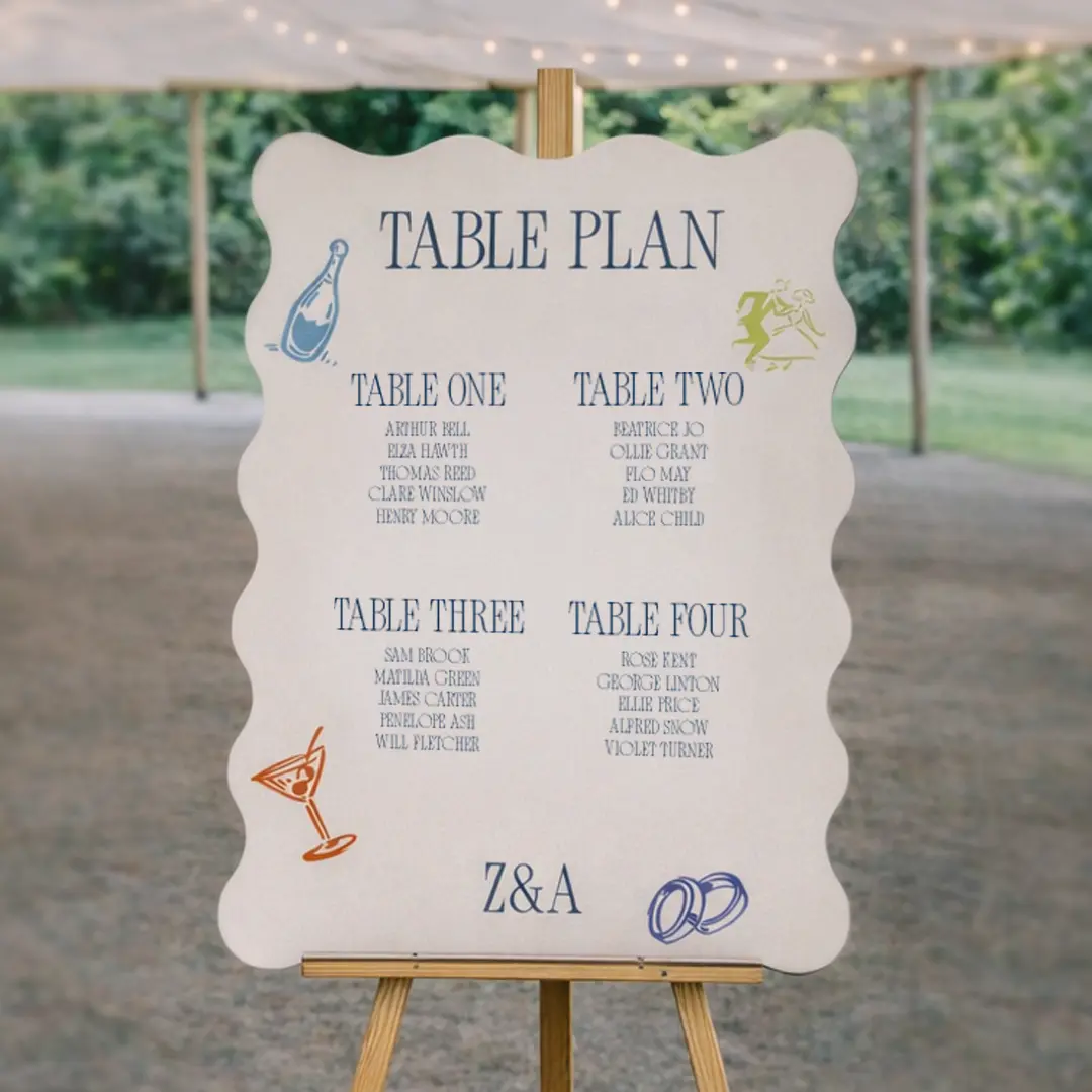 A wavy shape Wedding Table Plan Board displayed on an easel, featuring illustrated motifs like champagne, dancing, cocktails, and rings. The board lists four tables with guest names, with the couple’s initials “Z&A” at the bottom