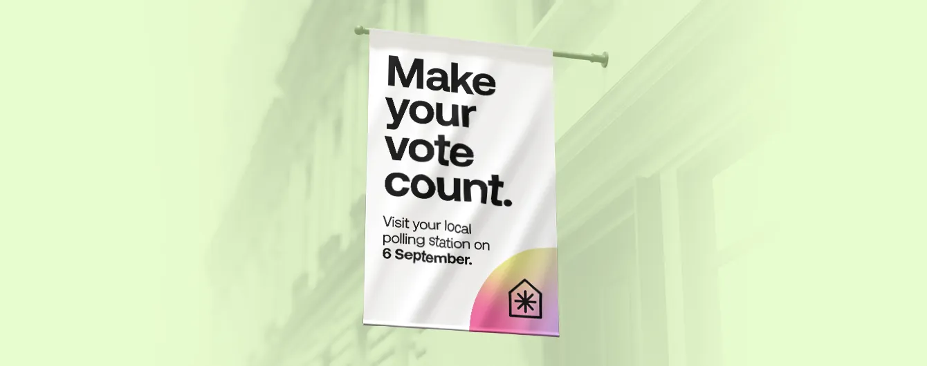 A vertical white banner hanging from a wall-mounted pole, featuring the slogan "Make your vote count" and an instruction to visit the local polling station on 6 September.