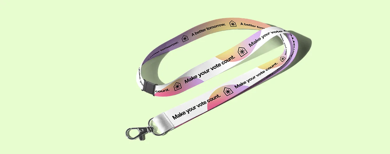 A branded fabric lanyard featuring a repeating "Make your vote count" slogan and campaign logo on a pink and yellow gradient background, complete with a silver metal swivel hook and a black plastic safety breakaway clip.