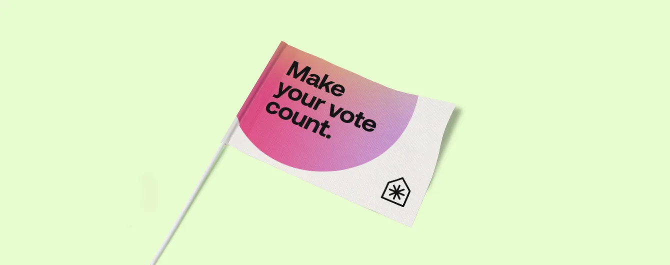 A small hand-held paper flag on a white stick, featuring a pink and yellow circular gradient with the campaign slogan "Make your vote count" in bold black text.