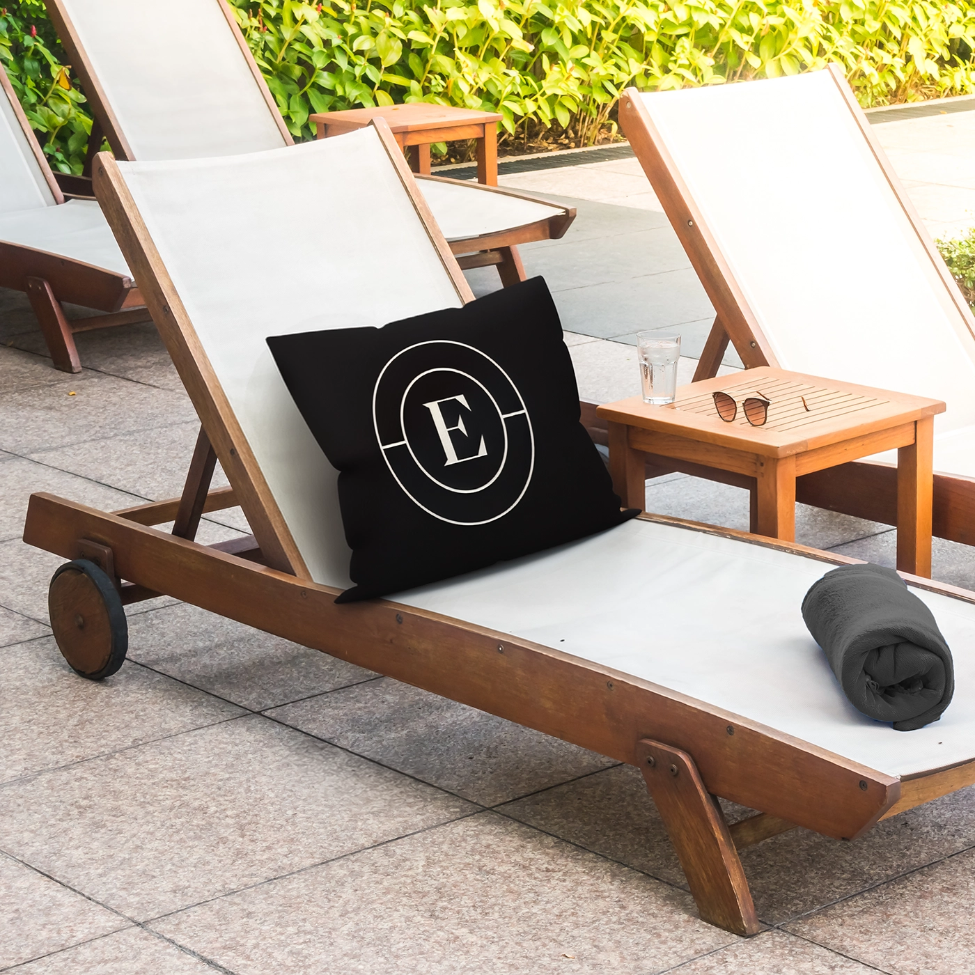 Outdoor lounge chair with a branded pillow in a sunny garden setting.