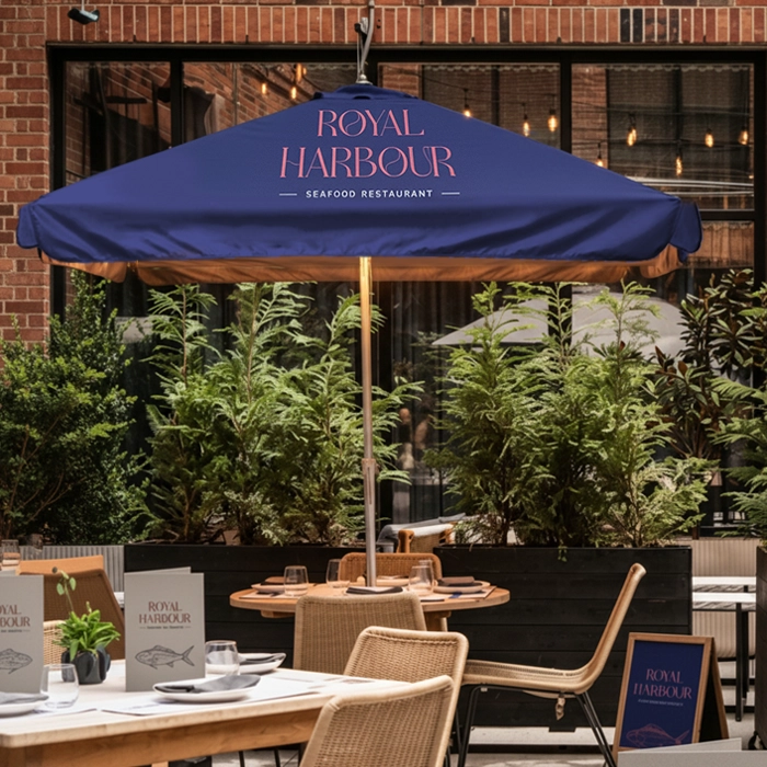 Outdoor restaurant tables under a blue commercial parasol with menus and greenery.