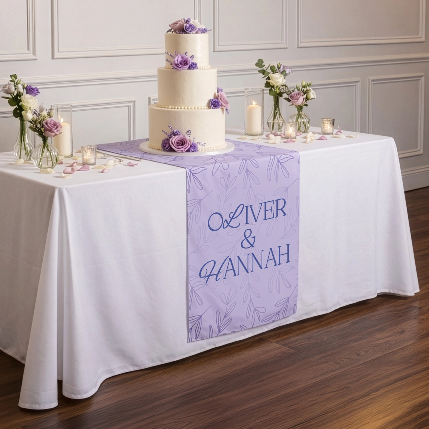 Wedding cake table with a personalised table runner for Oliver & Hannah, styled with flowers and candles.