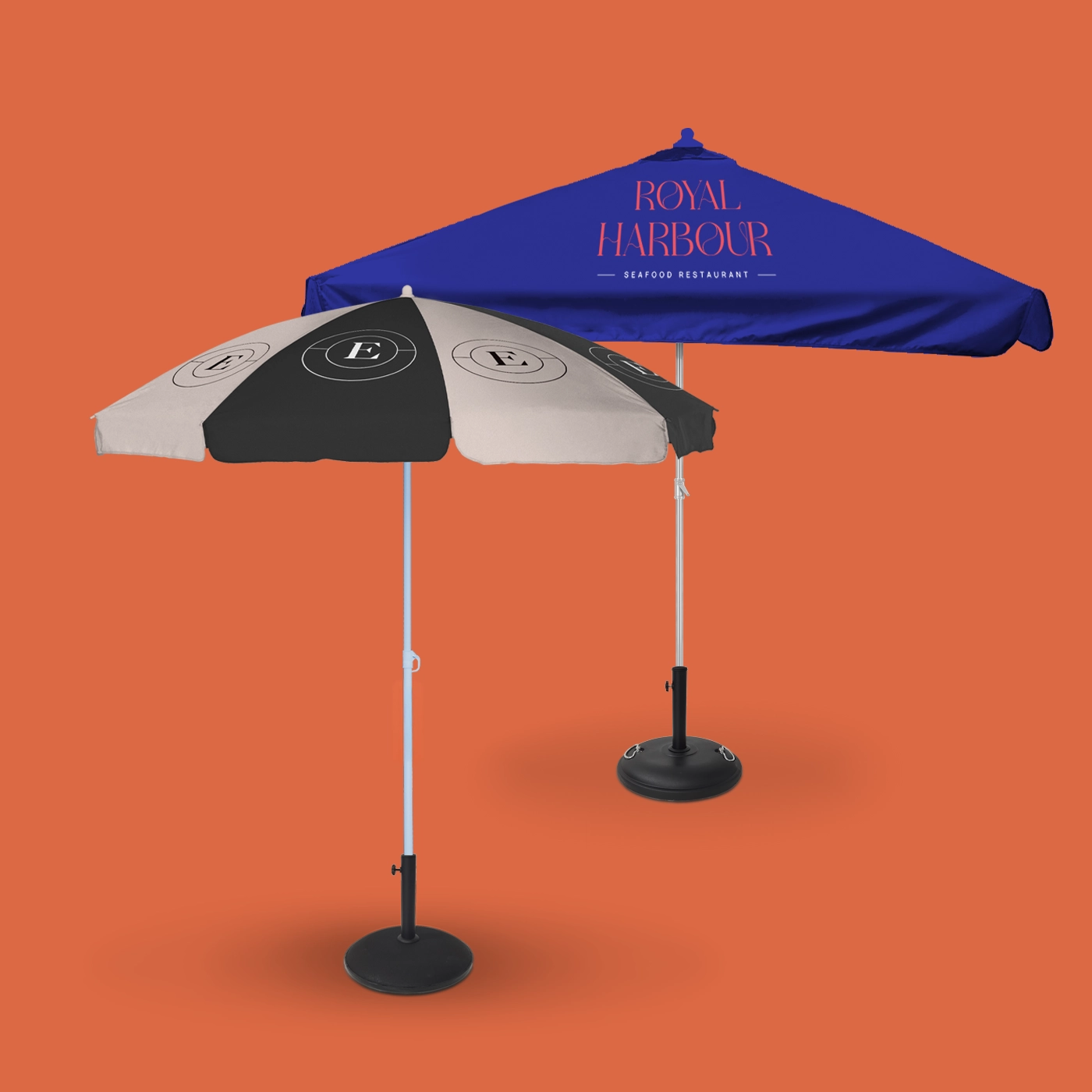 Two branded parasols, one with black and grey panels and the other a solid royal blue, are displayed against a vibrant orange background.