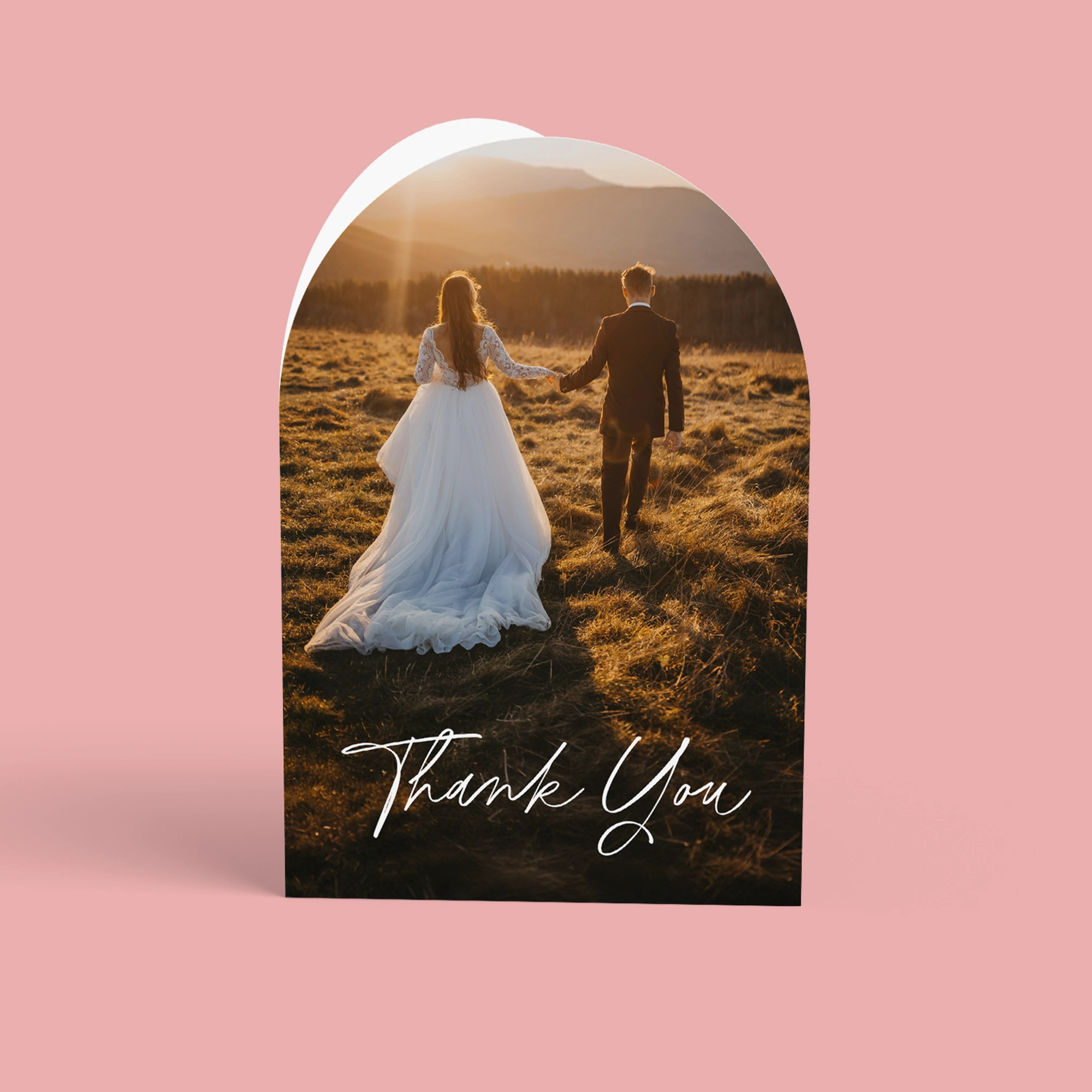 Upper arch-shaped Folded Wedding Thank You Card featuring a photo of a couple walking through a golden field at sunset, with "Thank You" written in white script at the bottom.