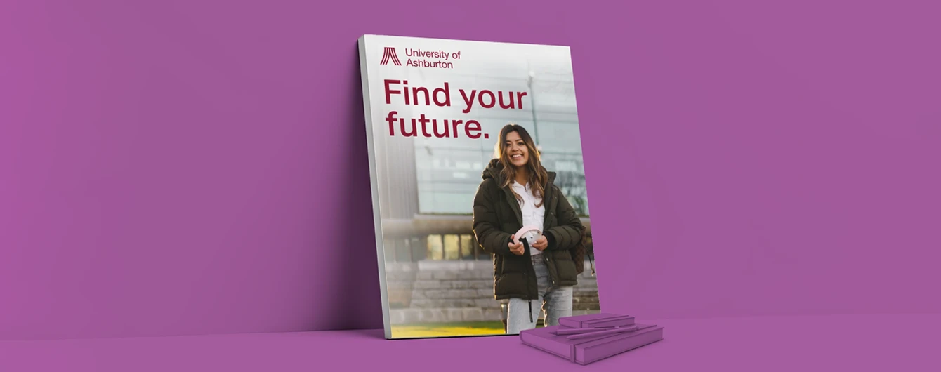 A large, sturdy foam board poster reading ‘Find your future’ for the University of Ashburton, leaning against a purple wall next to a small stack of purple notebooks.