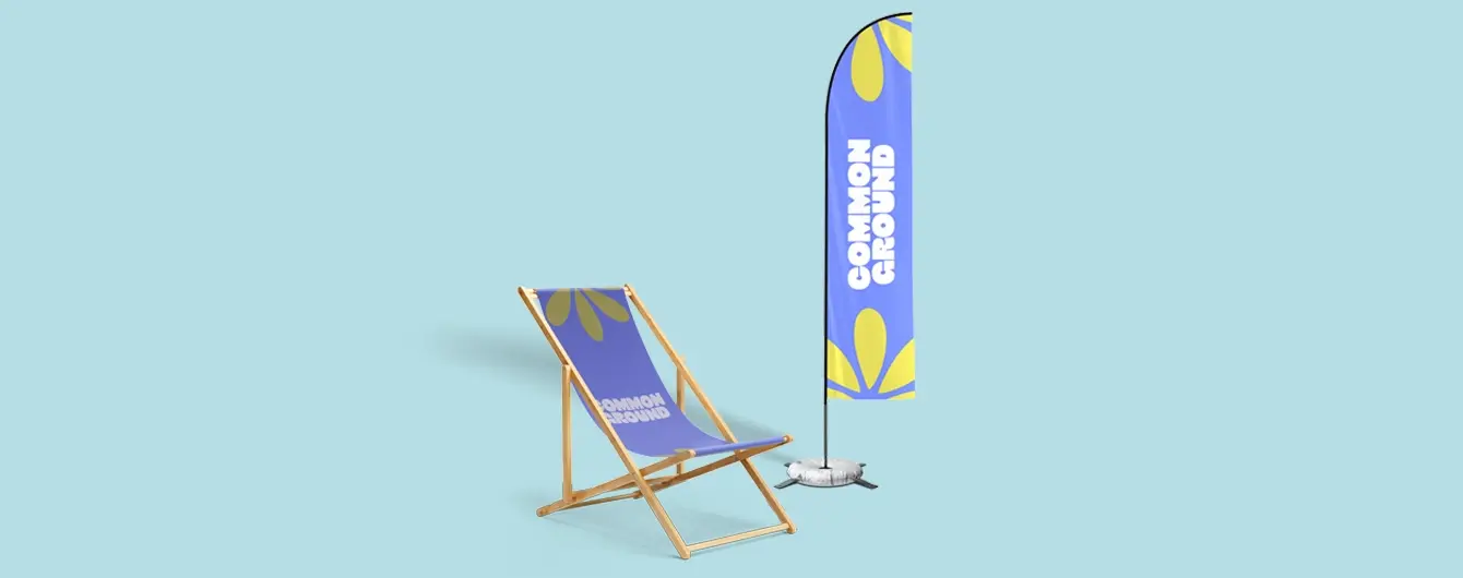 A blue fabric deckchair and a matching promotional feather flag, both printed with the 'Common Ground' logo and yellow floral motifs, set against a pale blue background.