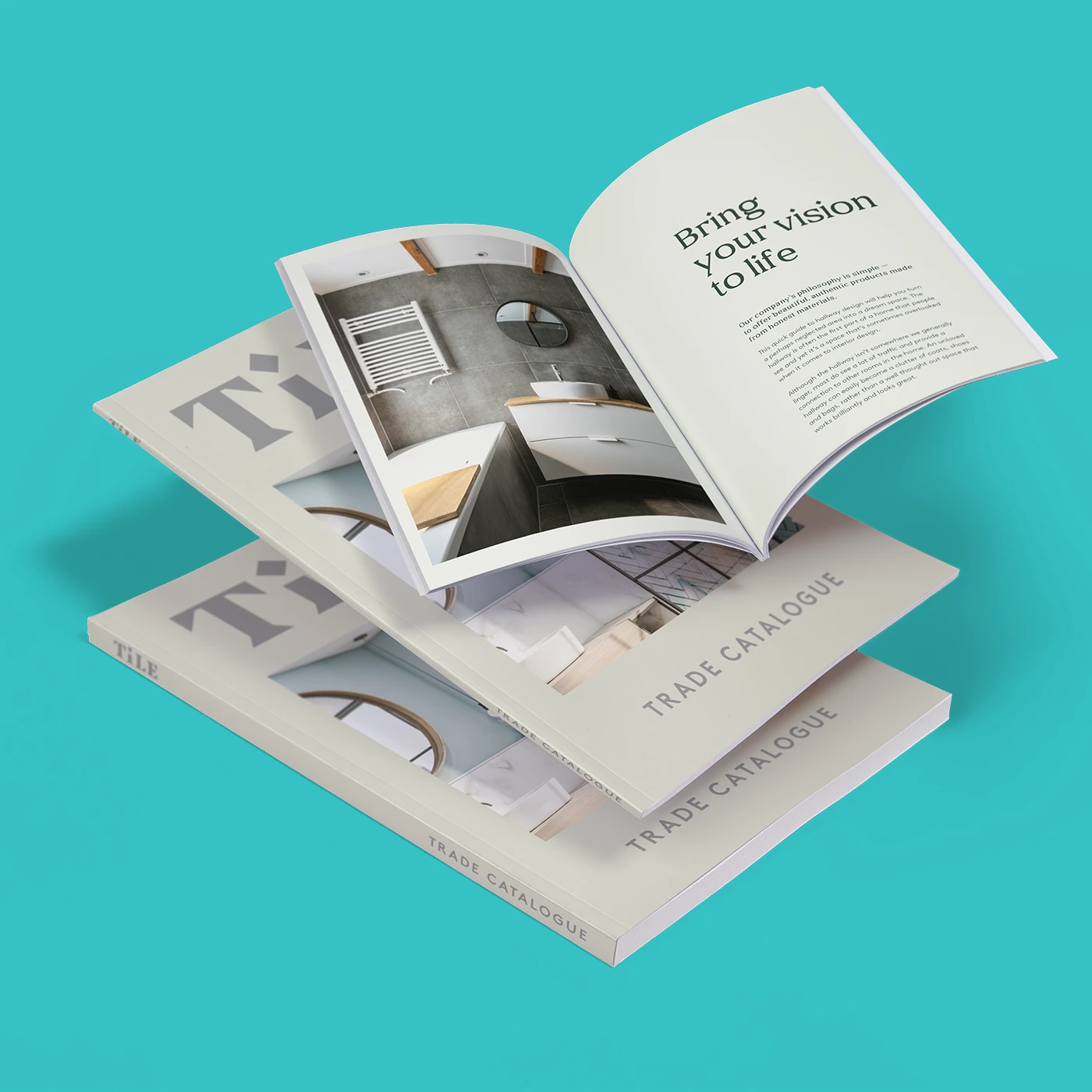 Three perfect bound trade Catalogues shown with one book open on top displaying a bathroom image and the headline "Bring your vision to life" against a bright turquoise background.