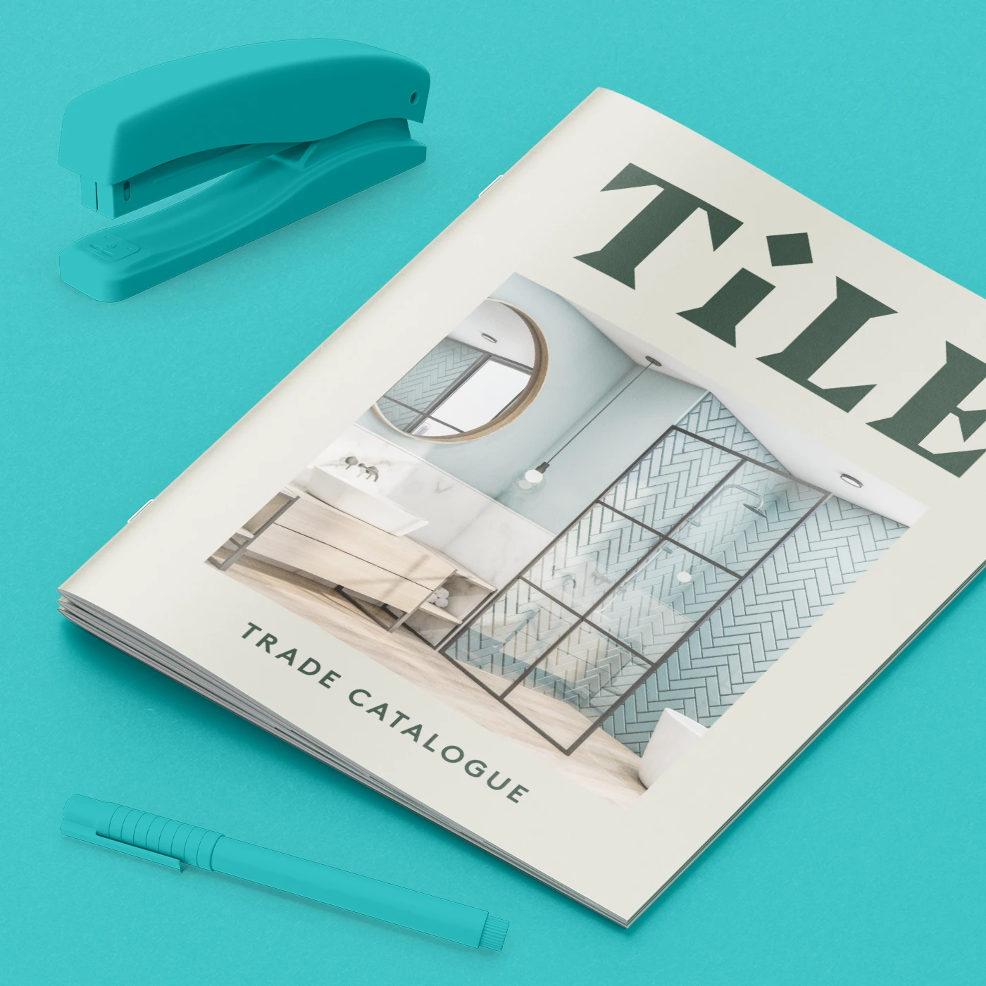 A Trade Catalogue booklet featuring a bathroom interior image displayed next to a matching stapler and pen.