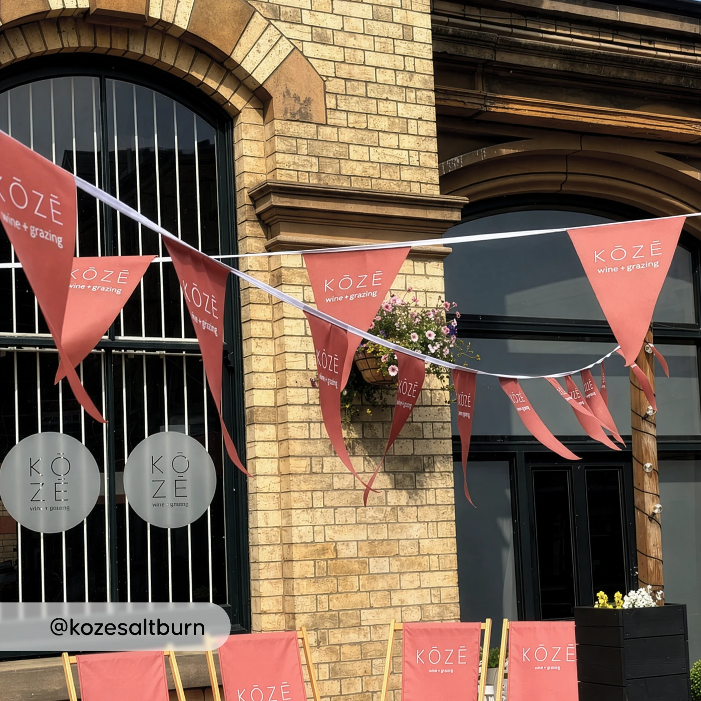 Red KOZE bunting and branded deck chairs outside a brick building with flowers