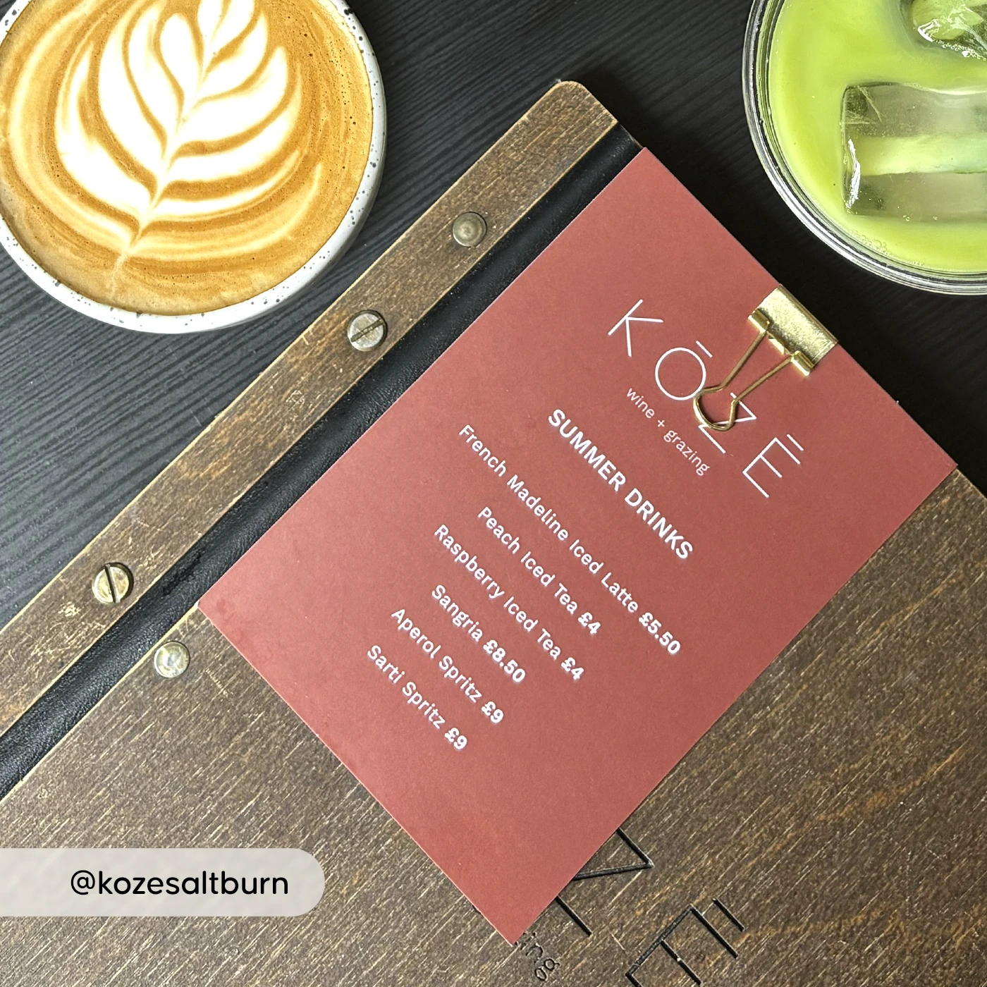 KOZE summer drinks menu on a clipboard beside a latte and iced matcha drink