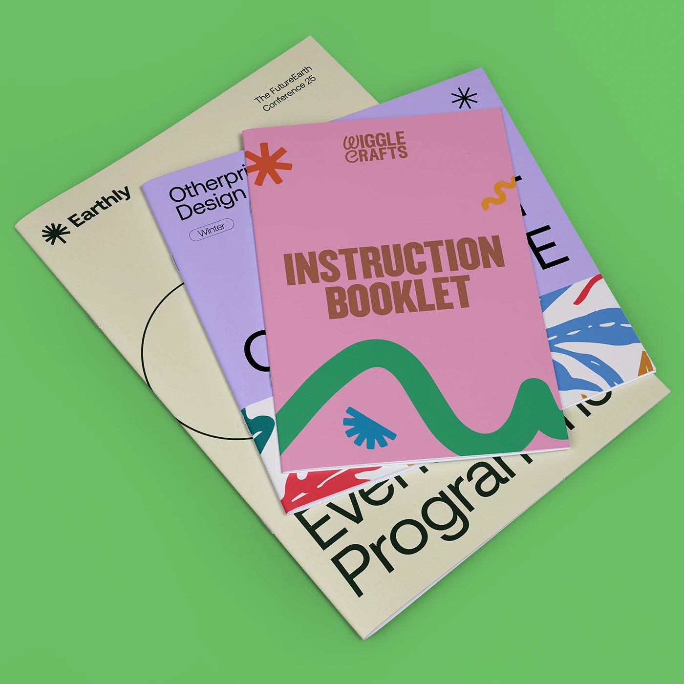Stack of three different size Saddle Stitch Booklets, including a pink cover reading "Giggle Crafts Instruction Booklet".