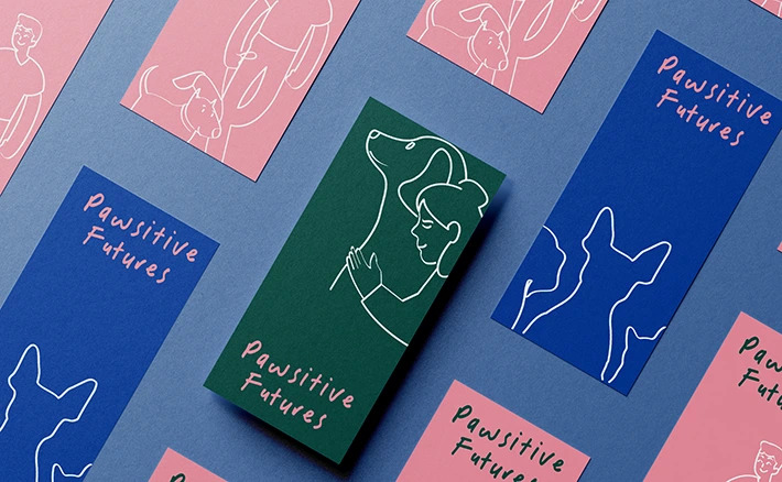 A collection of colourful printed cards featuring dog illustrations and the text "Pawsitive Futures" laid out on a blue background.