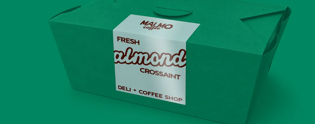 A green takeaway box sealed down the middle with a white label featuring the text "MALMO coffee FRESH almond CROISSANT DELI + COFFEE SHOP".