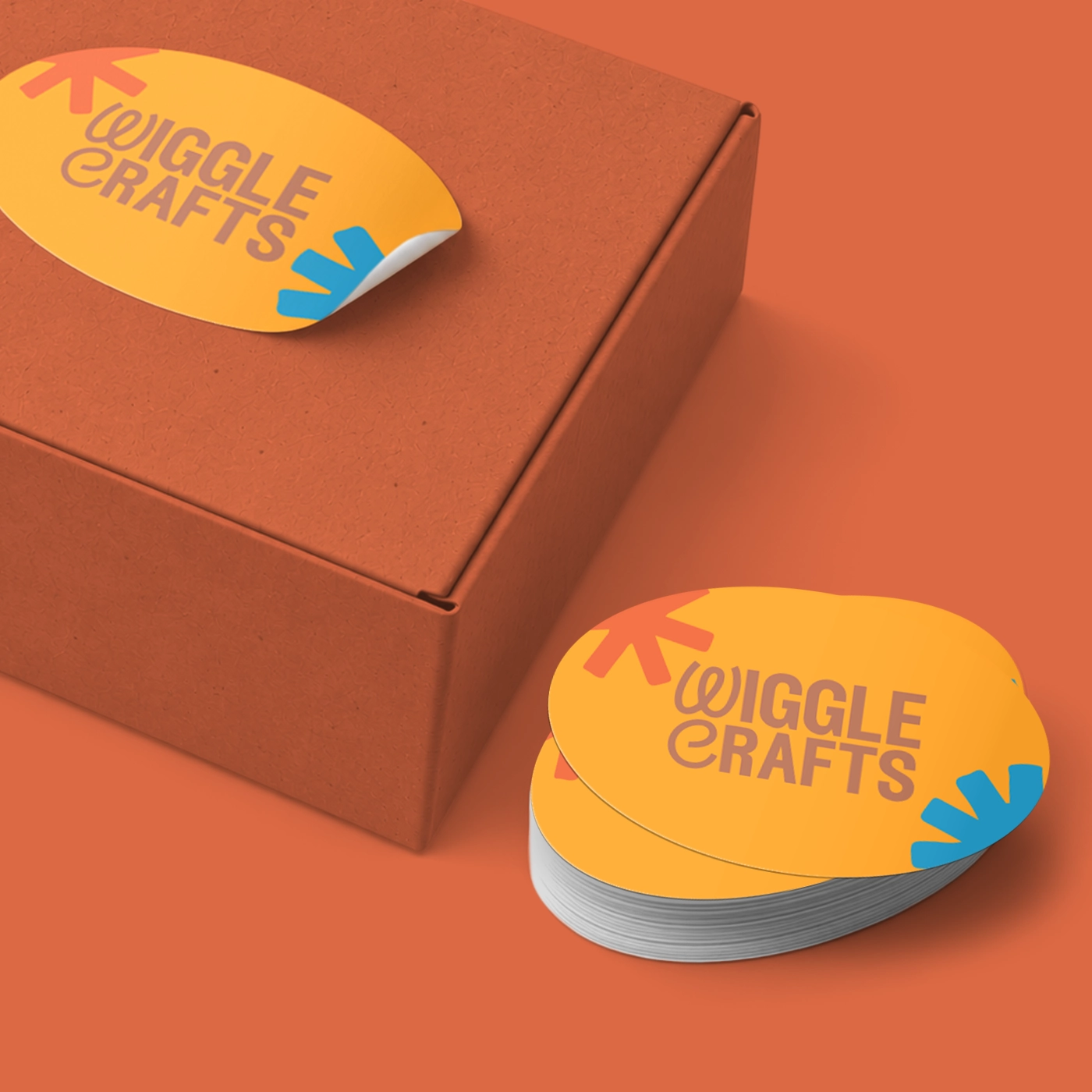 Orange Wiggle Crafts stickers shown on a box with a stack of matching labels beside it