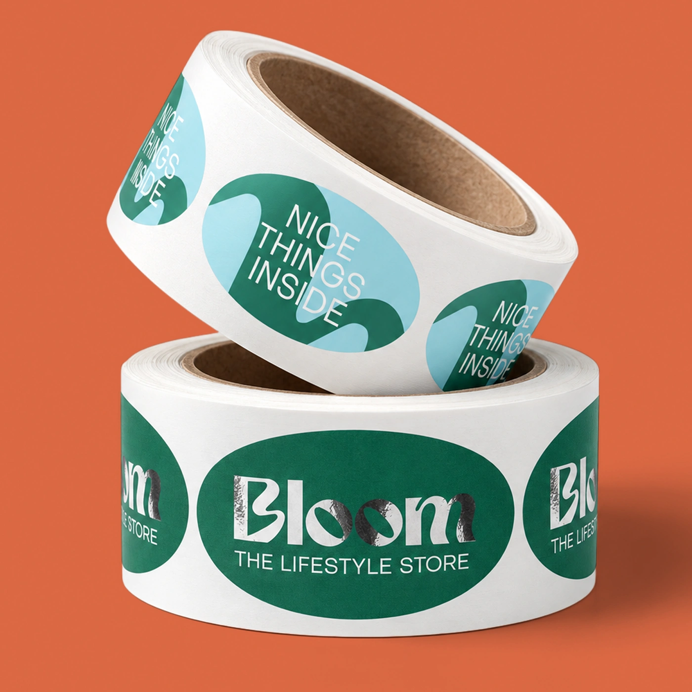 Two rolls of branded stickers for Bloom and Nice Things Inside against an orange backdrop
