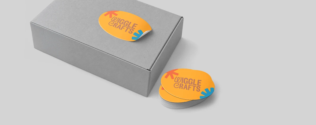 Orange Wiggle Crafts sticker partly applied to a grey box with a stack of labels nearby