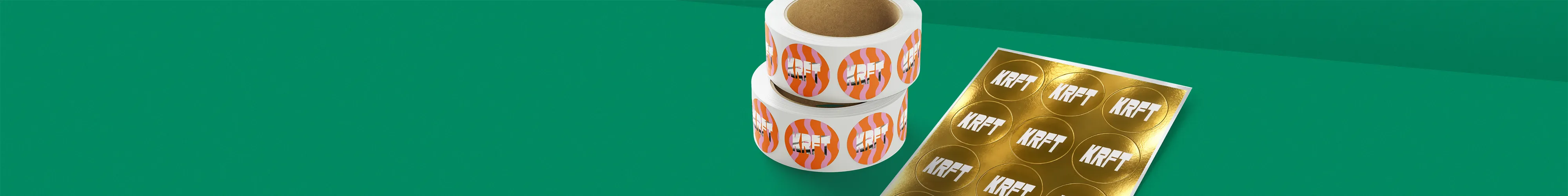 Two rolls of circular sticker labels alongside a gold foil sticker sheet, all displaying the text "KRFT", set against a green background.