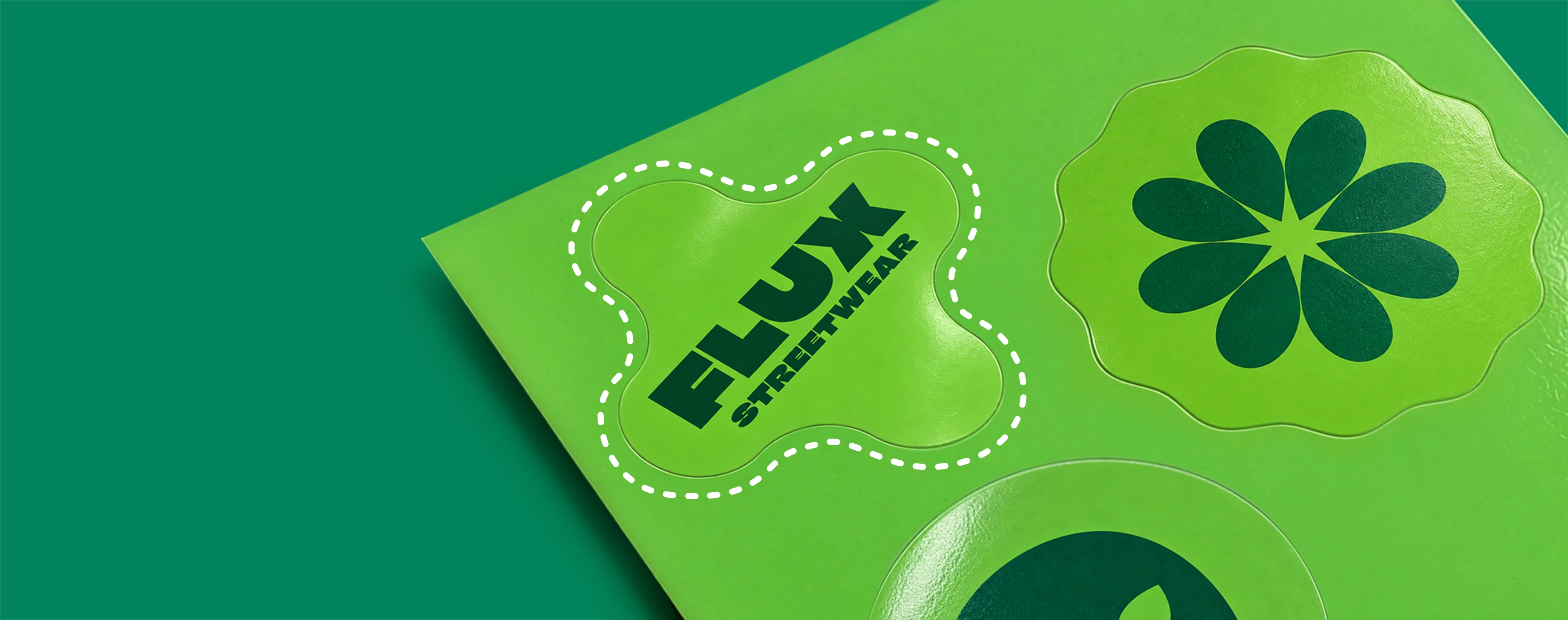 A sheet of green stickers featuring various shapes and designs, including one reading "FLUX STREETWEAR" outlines with a white dashed cut-line.