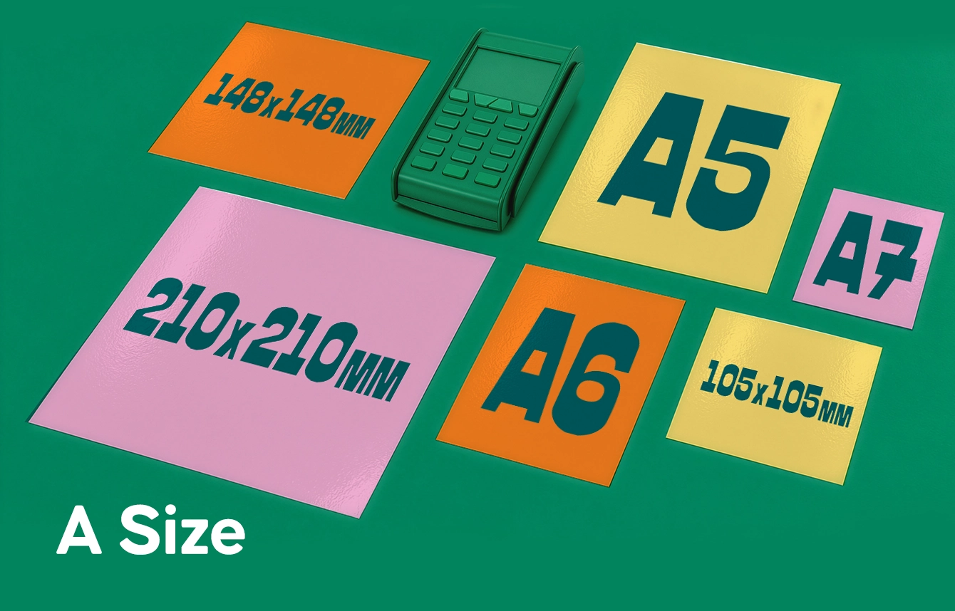 A collection of colourful square and A-standard sized stickers arranged on a green background next to a card payment terminal.