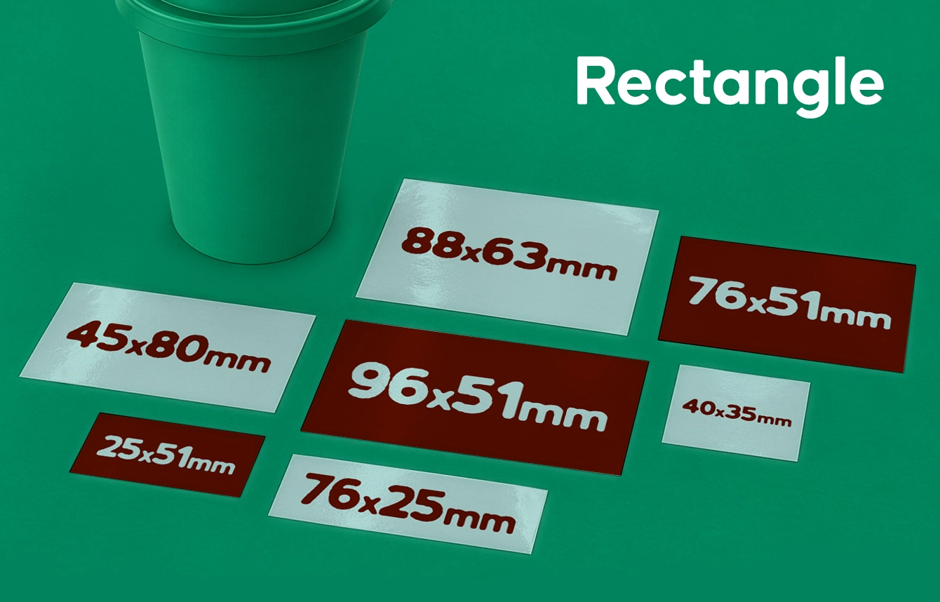 Seven rectangular stickers of various dimensions displayed on a green surface alongside a green cup.