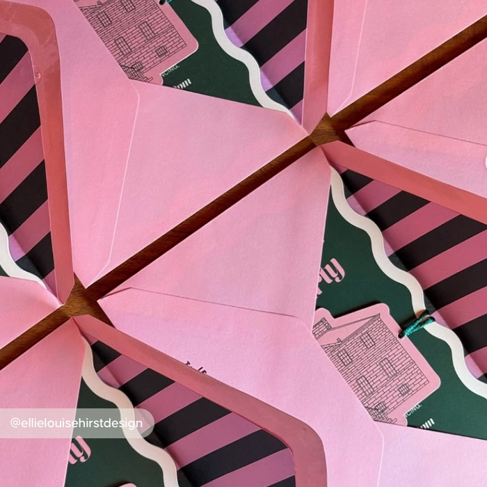 Open light pink Envelopes displaying custom striped Envelope Liners and wavy-bordered Invitation inserts tucked inside.