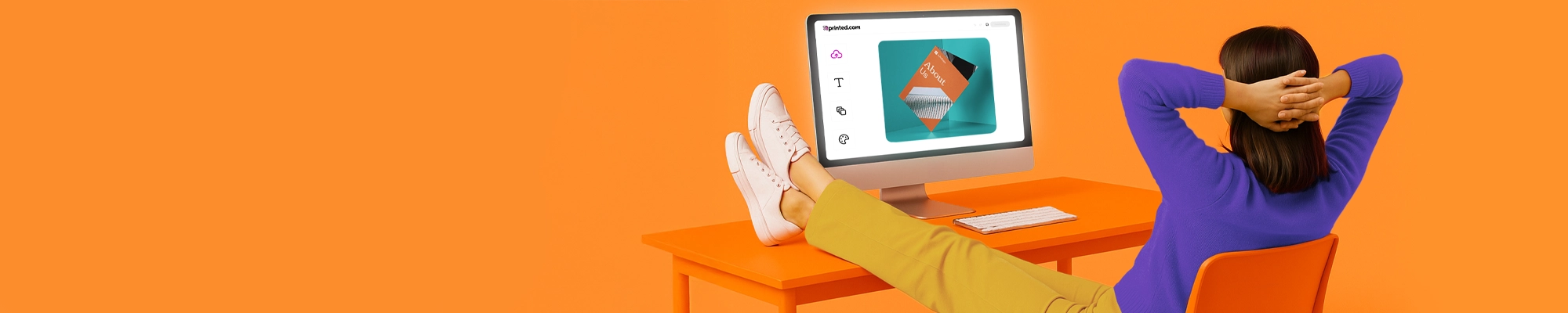 A person in a purple jumper resting with their feet up on an orange desk, looking at a computer screen displaying an online artwork editor, set against a bright orange background.