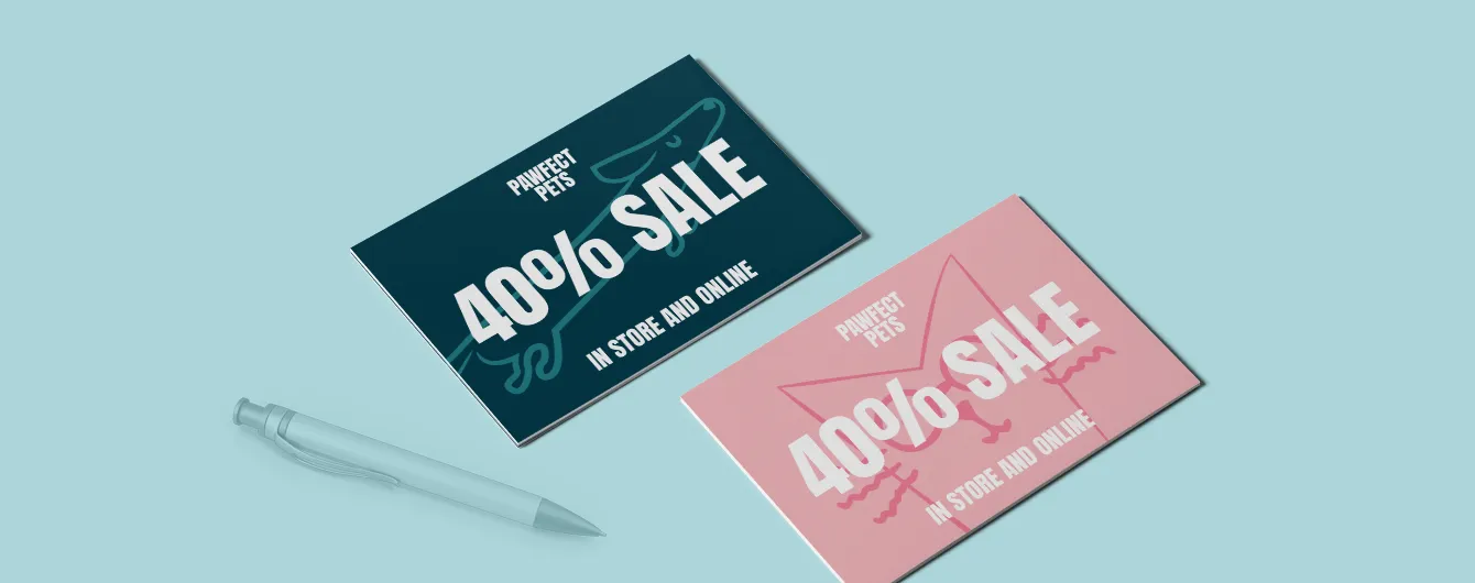 Two Pawfect Pets postcard-sized vouchers advertising a "40% SALE IN STORE AND ONLINE" laid out on a light blue background next to a pen.
