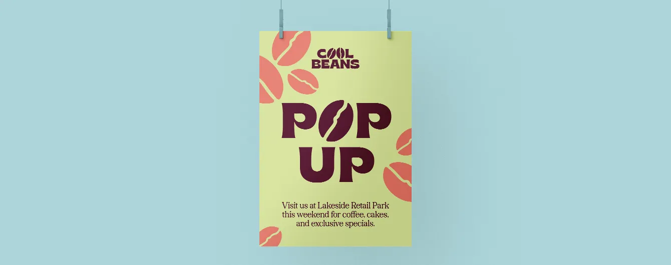 A yellow and red poster hanging from two clips, advertising a "Cool Beans POP UP" event at Lakeside Retail Park.