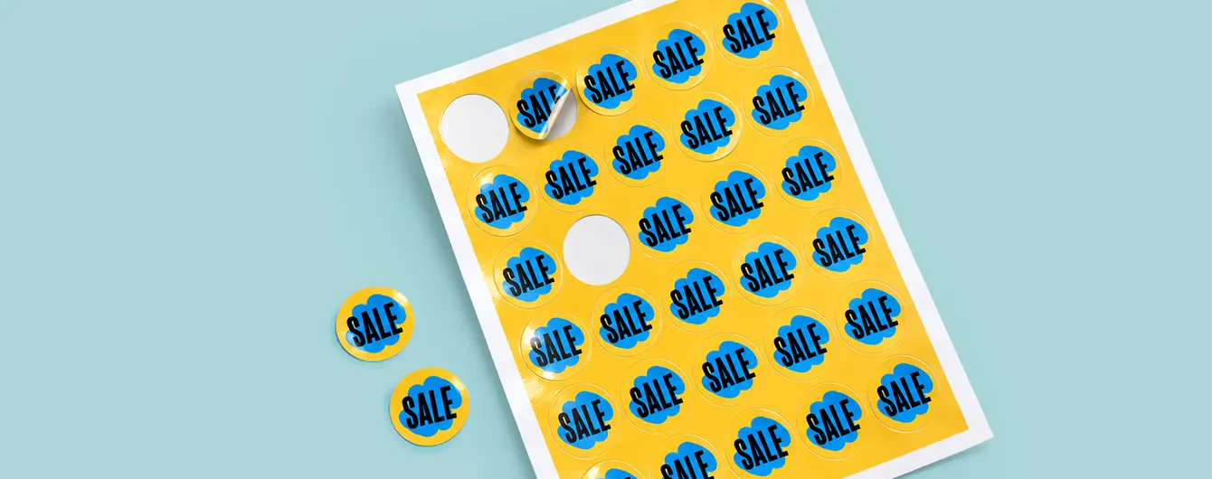 A sheet of round yellow promotional stickers featuring a blue cloud design with the word "SALE" printed on them.