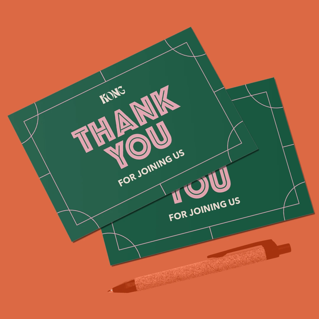 Two dark green Postcards with pink "Thank You for Joining Us" text, resting next to a pen.