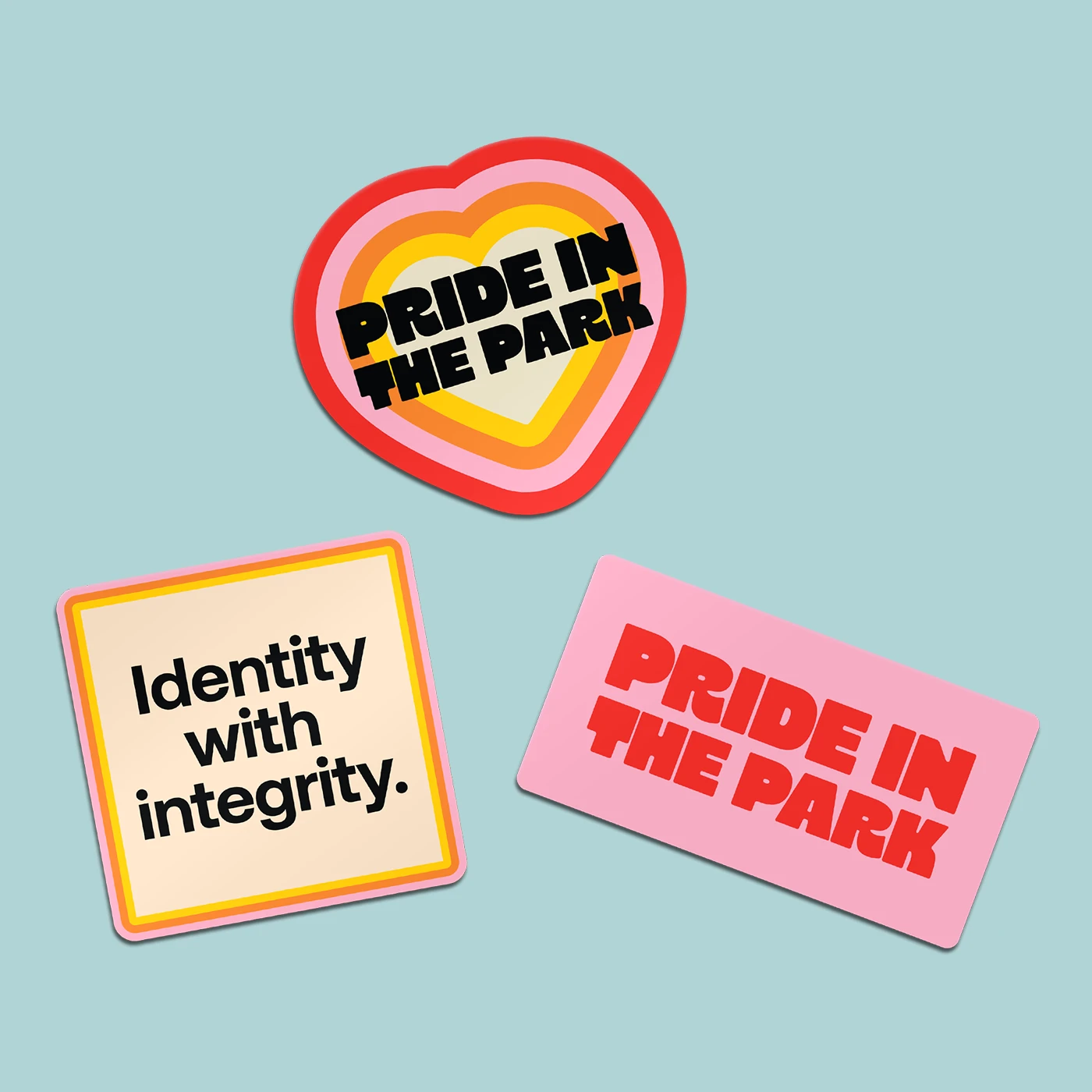 Three colourful Custom Shape Die Cut Stickers featuring "Pride in the Park" heart and rectangular designs alongside an "Identity with integrity" square Sticker.