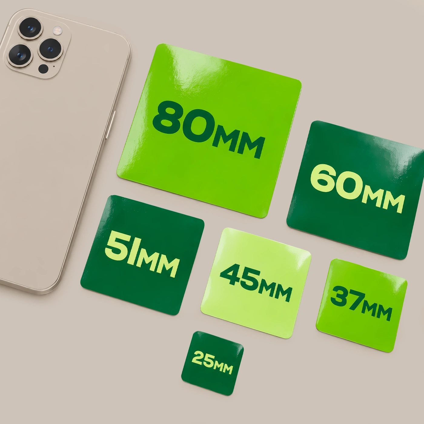 Six green Square Die Cut Stickers labelled 25mm, 37mm, 45mm, 51mm, 60mm and 80mm, arranged beside a smartphone.