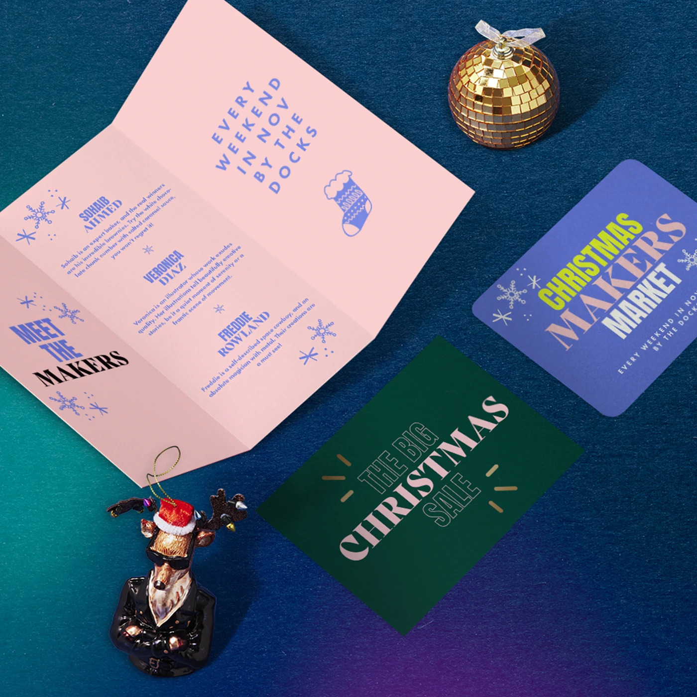An open Christmas event Folded Leaflet, two Christmas flat Leaflets, a gold disco ball, and a reindeer ornament sit on a dark blue background.