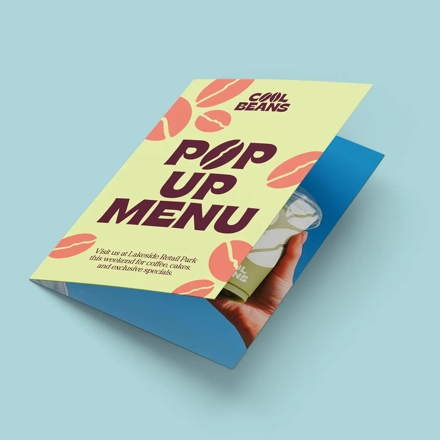 Folded Leaflet takeaway menu with bold typography and coffee bean illustrations, shown partially open to display the inside pages and print quality.