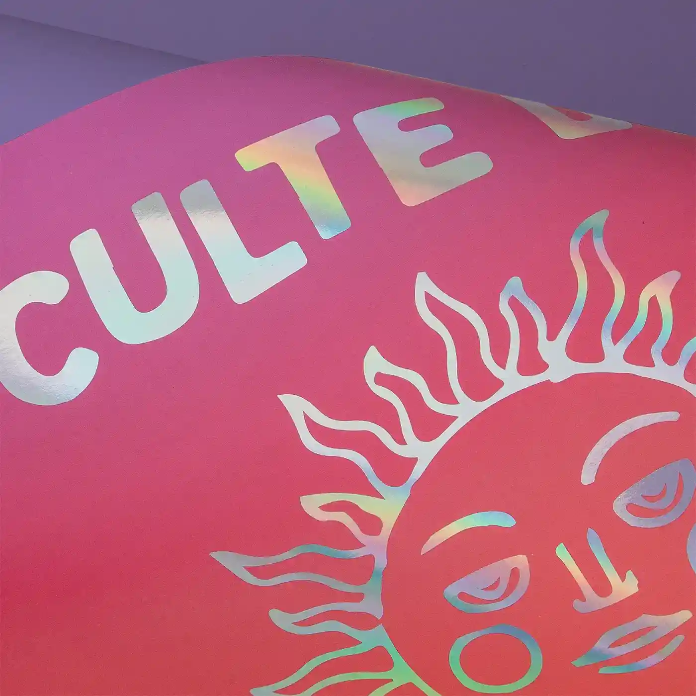 Close-up of a pink Foil Art Print featuring holographic foil and a stylised sun illustration against a purple background.