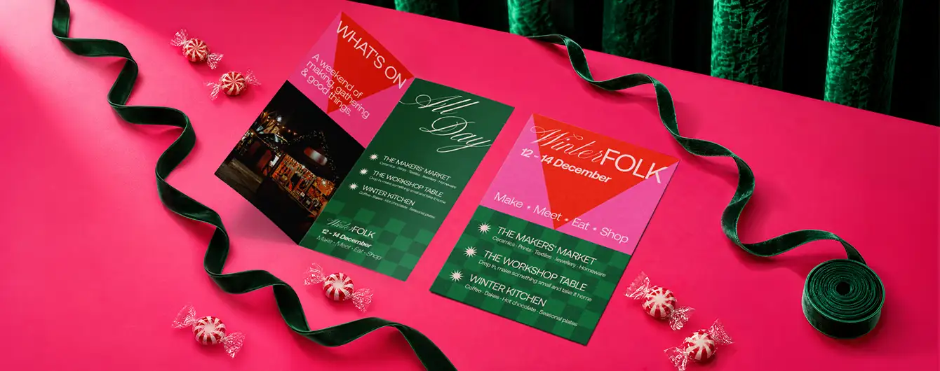 A "Winter FOLK" Christmas event Leaflet and Flyers, displayed on a pink surface.