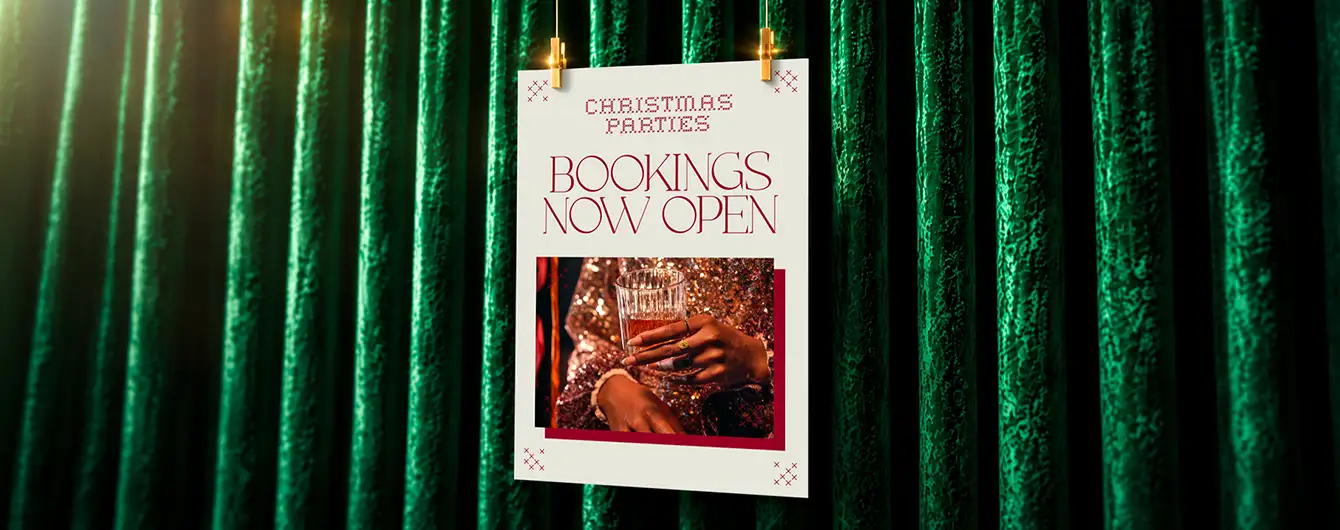 A "Christmas Parties - Bookings Now Open" Poster clipped to a festive green velvet curtain backdrop