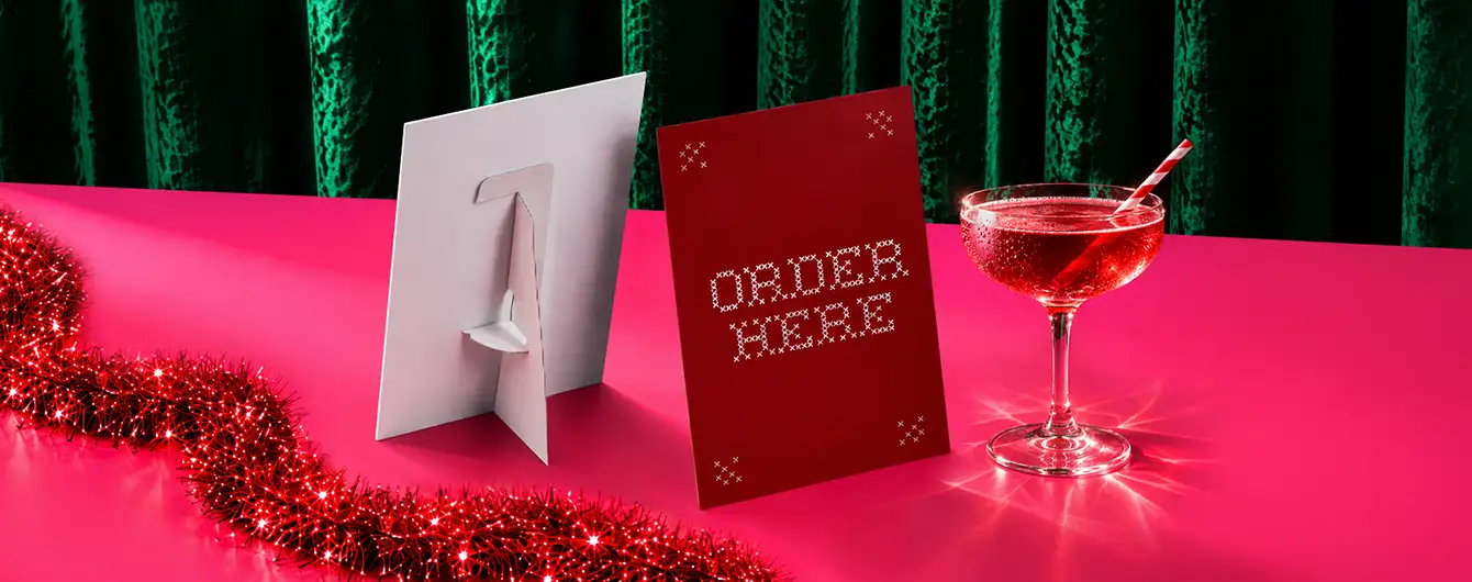 Christmas Strut Card displayed on a festive surface with red tinsel, a cocktail glass and a sparkling green backdrop.